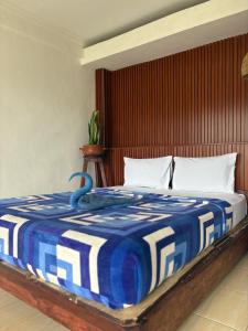 ein Bett mit einer blau-weißen Decke darauf in der Unterkunft Rinjani Houseboon in Senaru