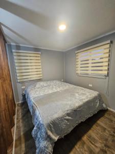 a bedroom with a bed and two windows at Refugio Titi3 in Coronel