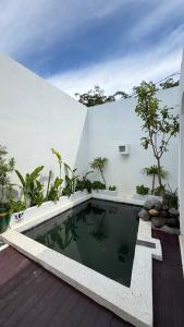 a swimming pool in front of a white wall at Zeman Villa in Padang