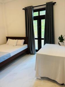 a bedroom with two beds and a window at Blue Cinnamon Cove in Kosgoda