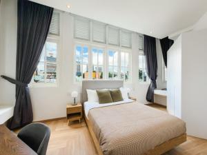 a bedroom with a large bed and windows at The White House - Serviced Residences by Cove & Belle Living in Singapore