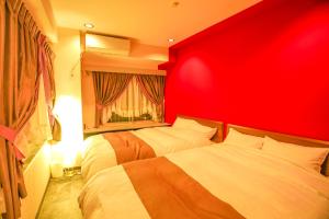 a bedroom with two beds with a red headboard at Nagoya Apartment Oosu in Minami-sotoborichō
