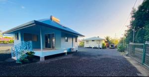 a blue house with a porch and a fence at Blue Sky Cozy in Paea