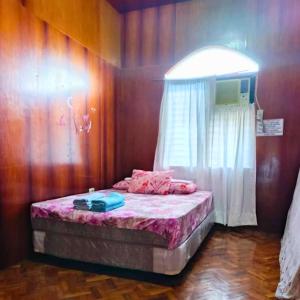 a bedroom with a bed with pink sheets and a window at Alaba Vacation House w Pool and Beach Access in Mambajao