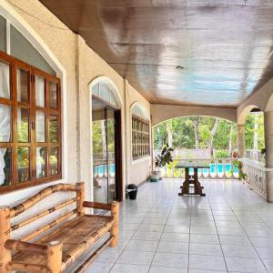 a room with benches and a table on a porch at Alaba Vacation House w Pool and Beach Access in Mambajao