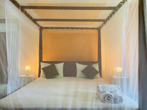 a bedroom with a canopy bed with two lamps at Sri Villa in Dickwella