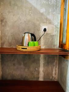 a tea kettle and cups on a wooden shelf at Sri Villa in Dickwella