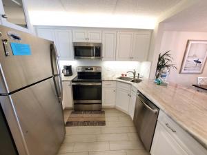 a kitchen with white cabinets and a stainless steel refrigerator at Summerhouse 104- Direct Oceanfront condo in St. Augustine