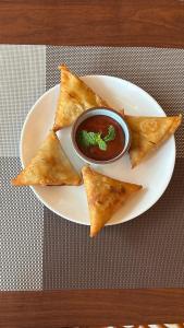 a white plate with a plate of food with dips at Eva Beach Side Room in Mandrem