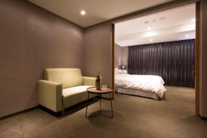 a bedroom with a bed and a chair and a table at Noble Hotel in Taipei