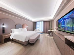 a hotel room with a bed and a flat screen tv at Mercure Xi'an Stadium Hotel in Xi'an