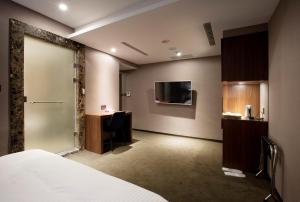 a hotel room with a bed and a desk and a tv at Noble Hotel in Taipei