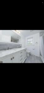 a white bathroom with a sink and a toilet at The Carneys Point Cottage in Friendship Station