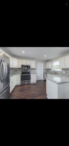 a kitchen with white cabinets and a stainless steel refrigerator at The Carneys Point Cottage in Friendship Station