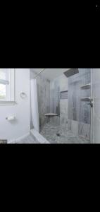 a white bathroom with a shower and a sink at The Carneys Point Cottage in Friendship Station