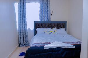 a bedroom with a large bed with blue curtains at Happy Home Ke in Isiolo