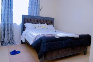 a bedroom with a large bed with blue curtains at Happy Home Ke in Isiolo