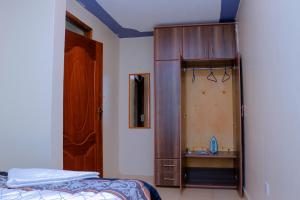 a bedroom with a bed and a wooden cabinet at Happy Home Ke in Isiolo
