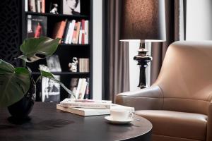 a coffee table with a cup and a plant and a chair at Roomers Berlin Steinplatz, Autograph Collection in Berlin