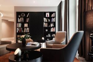 a living room with chairs and a table and bookshelves at Roomers Berlin Steinplatz, Autograph Collection in Berlin