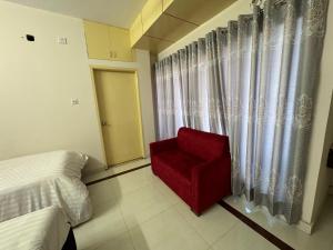 a bedroom with a red chair in front of a window at Hotel Sarbick International in Kukrāil