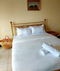 a white bed with a rolled up towel on it at Casa Rosa in Nanyuki