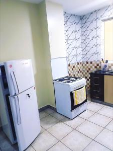 a kitchen with a white refrigerator and a stove at Casa Rosa in Nanyuki +6 photos