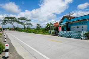an empty road in front of a blue building at RedDoorz near RSUD Kebumen 2 in Wanasari +17 photos
