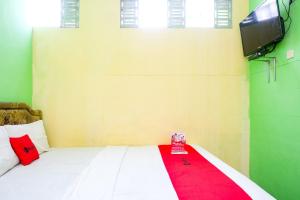 a bedroom with a white bed with a red blanket at RedDoorz near RSUD Kebumen 2 in Wanasari