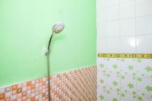a shower in a tiled bathroom with at RedDoorz near RSUD Kebumen 2 in Wanasari