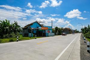 an empty street with a blue building and cars on the road at RedDoorz near RSUD Kebumen 2 in Wanasari