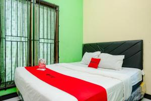 a bedroom with a bed with a red blanket on it at RedDoorz near RSUD Kebumen 2 in Wanasari