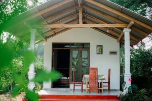 a house with a wooden roof and a table and chairs at Diyana Cottage in Sigiriya