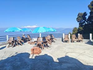 a group of chairs and umbrellas on a patio at Lamahatta Clouds Hotel & Restaurant in Takdāh