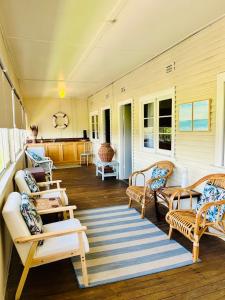 a porch with benches and chairs on a house at Bermagui Bay Beach House 2, Wonderful Beachside Location, Pet Friendly in Bermagui
