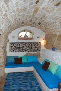 Villa Spiti Elaionas في كارفاس: أريكة زرقاء في غرفة بجدار حجري