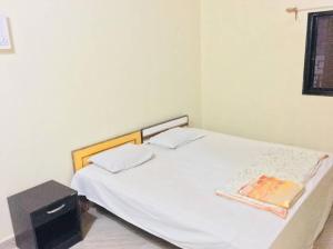 a bedroom with a white bed with a wooden headboard at Homestay, Villa in Diveagar in Diveagar