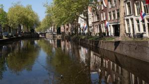 a canal in a city with buildings and trees at Studio De Gravin in Gouda +5 photos