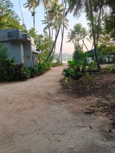 a dirt road next to a building with palm trees at Lagoon lake view in Kollam
