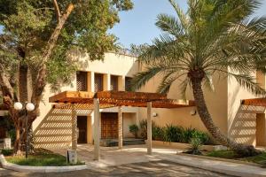 a building with palm trees in front of it at Le Meridien Al Khobar in Al Khobar