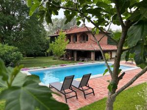 a pool with two chairs and a house at Casa Ambrogina in Agliano Terme