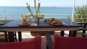 a wooden table with two plates of food on top of the ocean at Kefalonia Beach Hotel & Bungalows in Lixouri