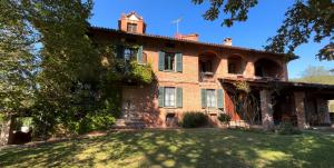 an old red brick house with a grass yard at Casa Ambrogina in Agliano Terme