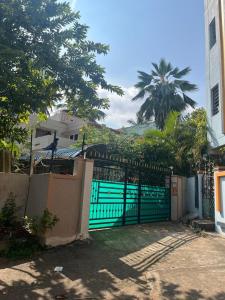 a green gate in front of a house with a palm tree at Chill Vibes in Visakhapatnam