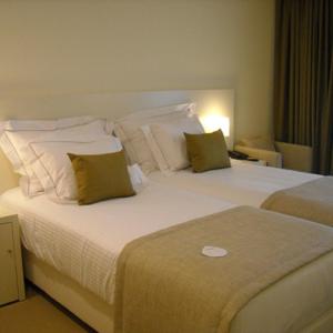 um quarto de hotel com uma grande cama branca com almofadas em INLIMA Hotel & Spa em Ponte de Lima