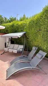 two lounge chairs and an umbrella on a patio at Casa Luxemburgo in Torrevieja