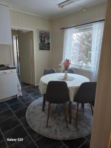 a dining room table with chairs and a vase of flowers on it at Auroraheim in Gryllefjord