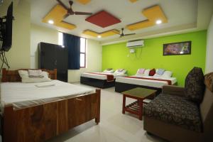 a hotel room with three beds and a chair at Hotel Madurai Comforts in Madurai