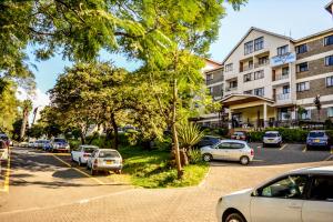 un estacionamiento con autos estacionados frente a un edificio en YWCA Parkview Suites, en Nairobi