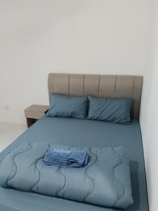 a bed with a blue comforter and blue pillows at D'Tarbiyyah Homestay in Labu